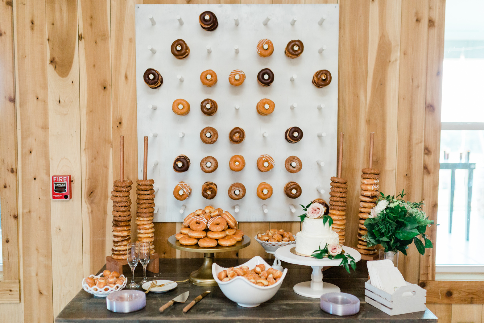 Wood Wall with a Donut Wall Party Decoration at a Wedding Reception with Donuts and Cake on a Table